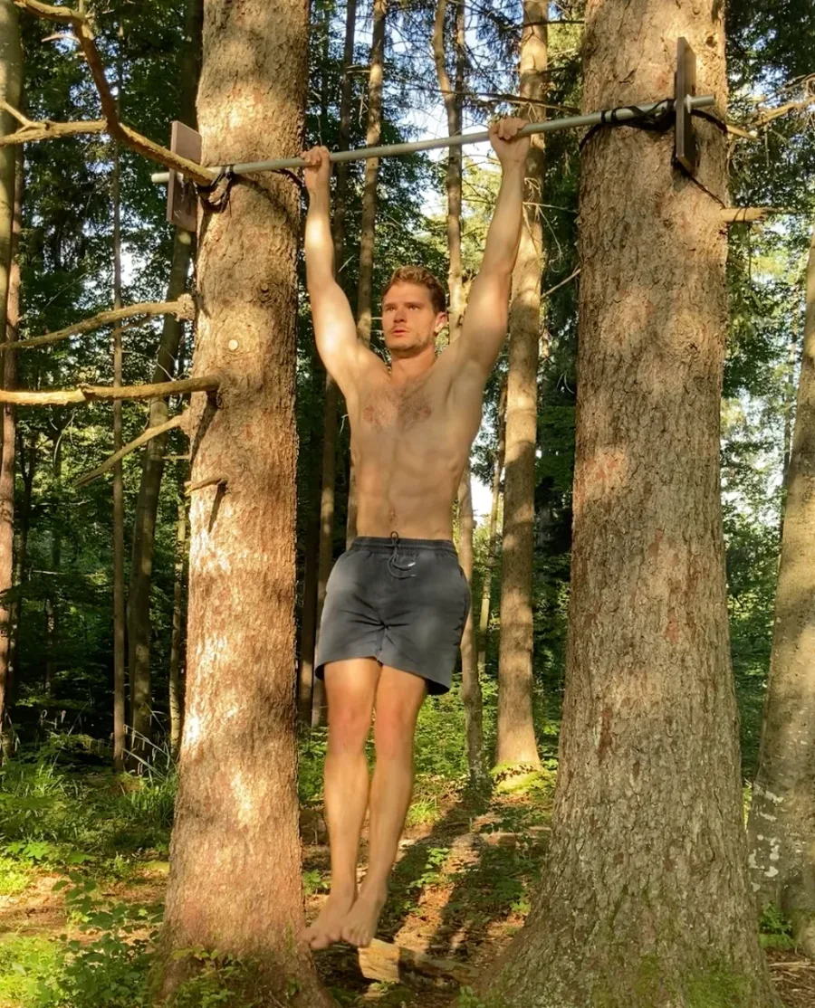Nils training with bodyweight movements on a tree in the forest, no gym equipment