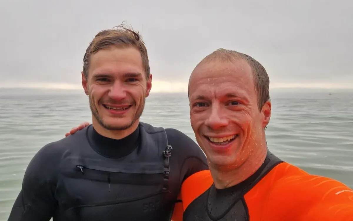 Nils with his client Max in wetsuits at the lake after an open-water training session